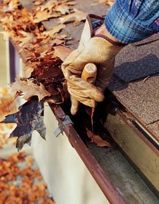 A gutter being cleared by hand of leaf litter and silt