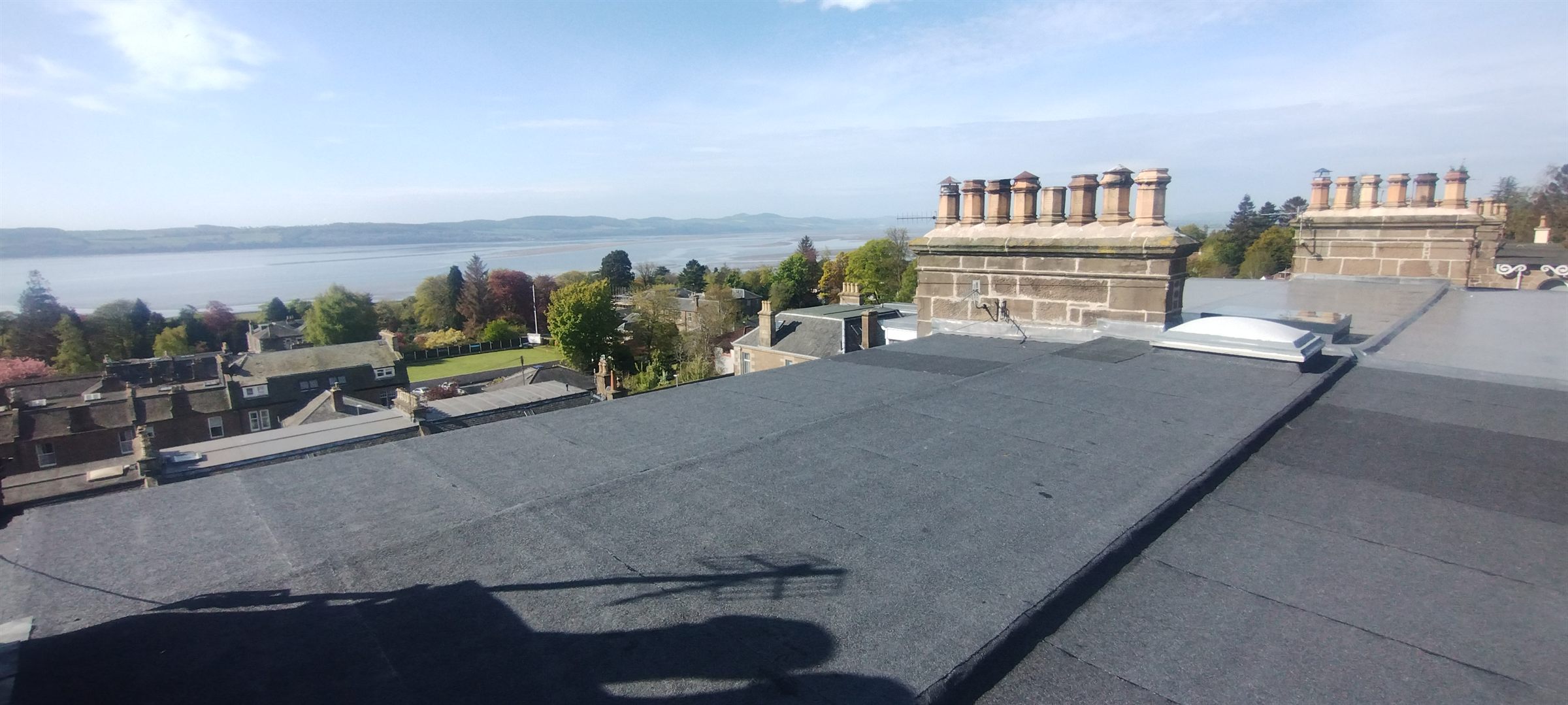 A flat roof renewed by Dundee Roofing Services, looking out across the Tay estuary past sandstone chimney stacks