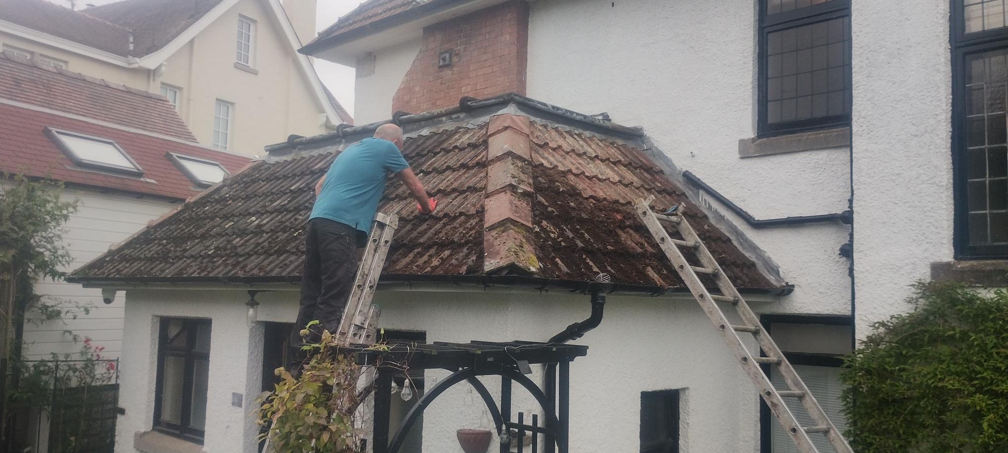 Porch roof stripped of moss — Years of growth lifted off by hand with a trowel and brush. No pressure washer near the tiles — it forces water underneath them.